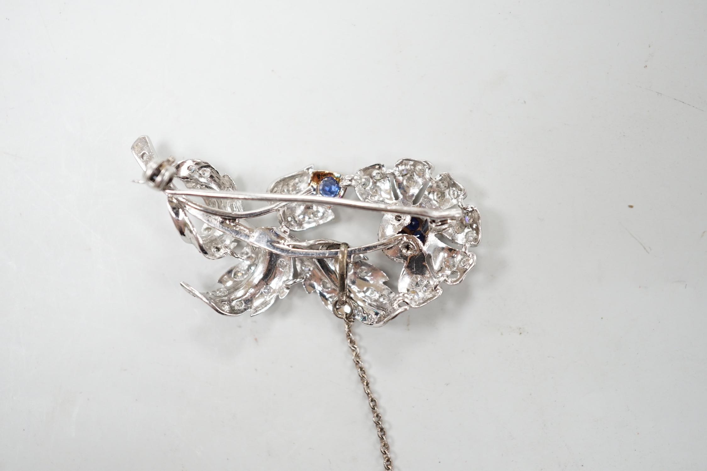 A modern white metal, sapphire and diamond chip set floral spray brooch, 43mm, gross weight 8.8 grams.